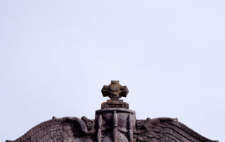 a stone sculpture of an hourglass with bird wings